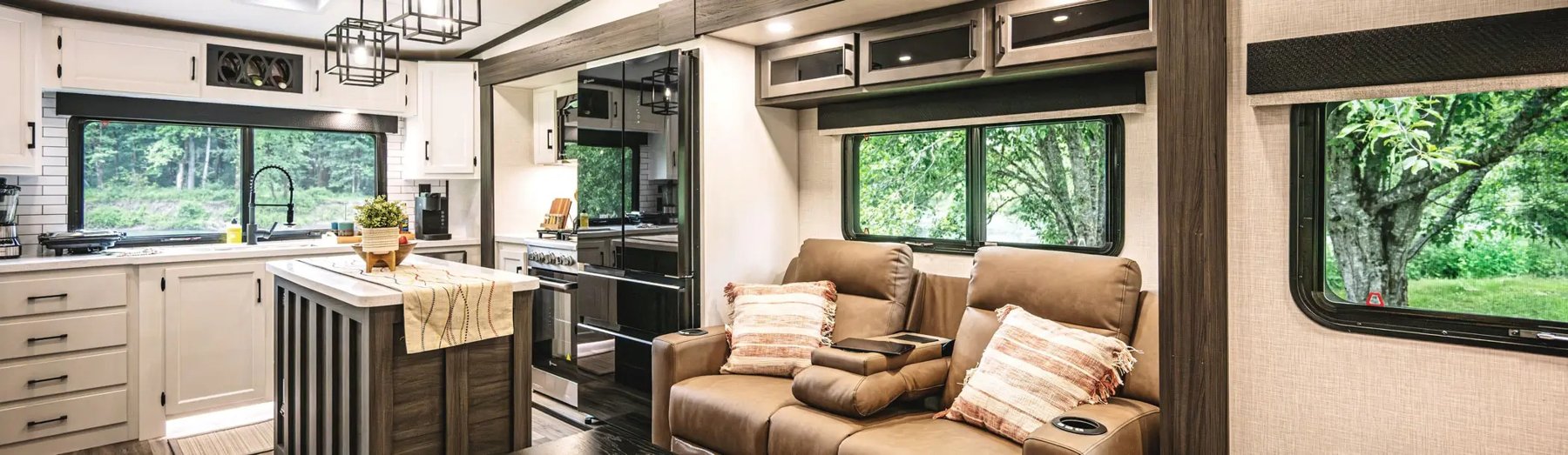 Interior of a new Venture RV travel trailer: theater seating, kitchen, and large windows