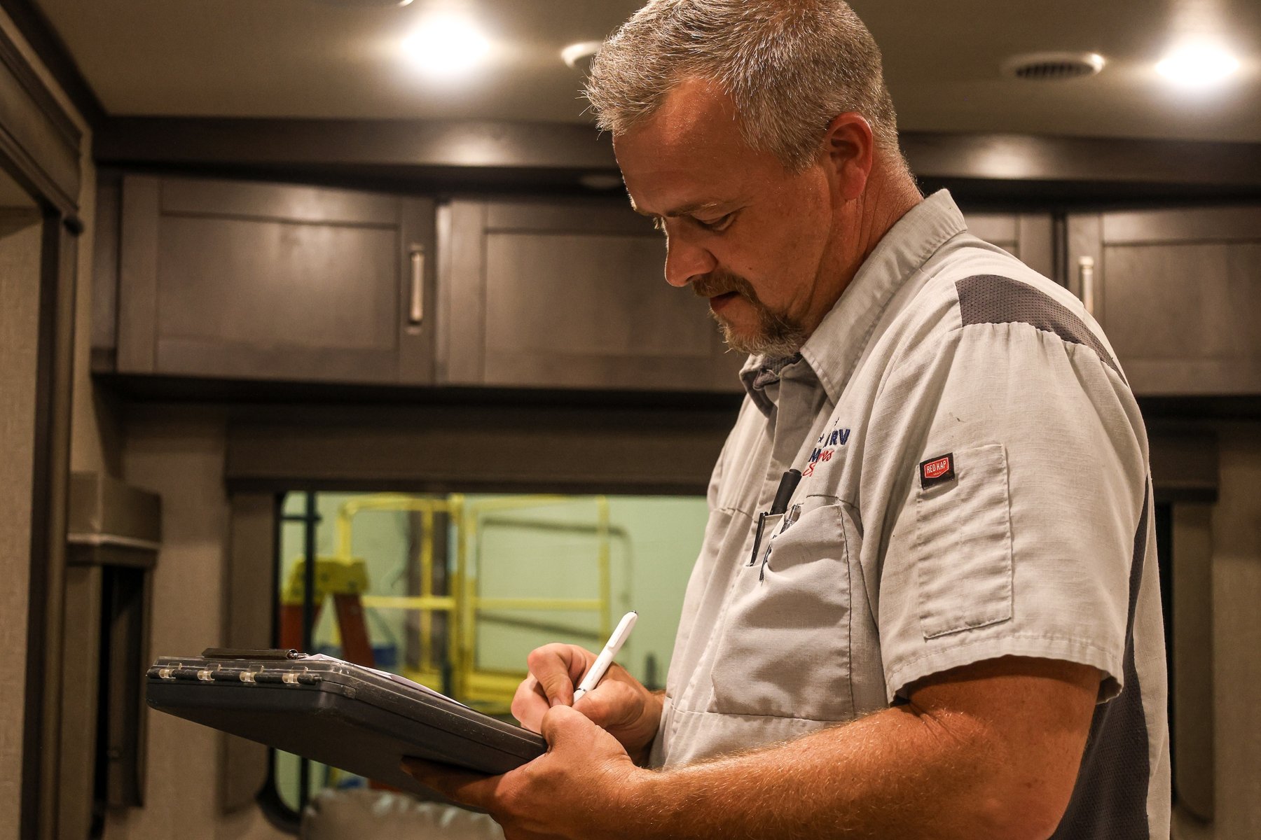 Great American RV technician inspecting an RV interior with a checklist